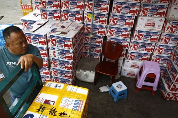 A man waits for the goods to be load on his tricycle at a dealer selling imported seafoods at the Jingshen seafood market in Beijing, Thursday, July 12, 2018. [Photo: AP/Andy Wong]